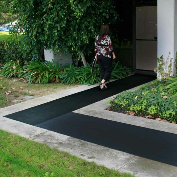 Woman walking to a door entrance lined with black corrugated fine rib rubber runner mats