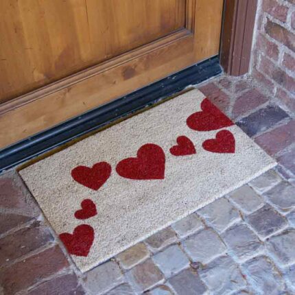 Beige Doormat with red heart designs in front of brown door