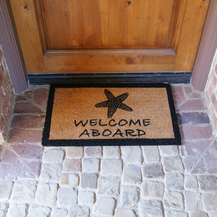 Welcome Aboard sign with sea side shell in front of light brown door
