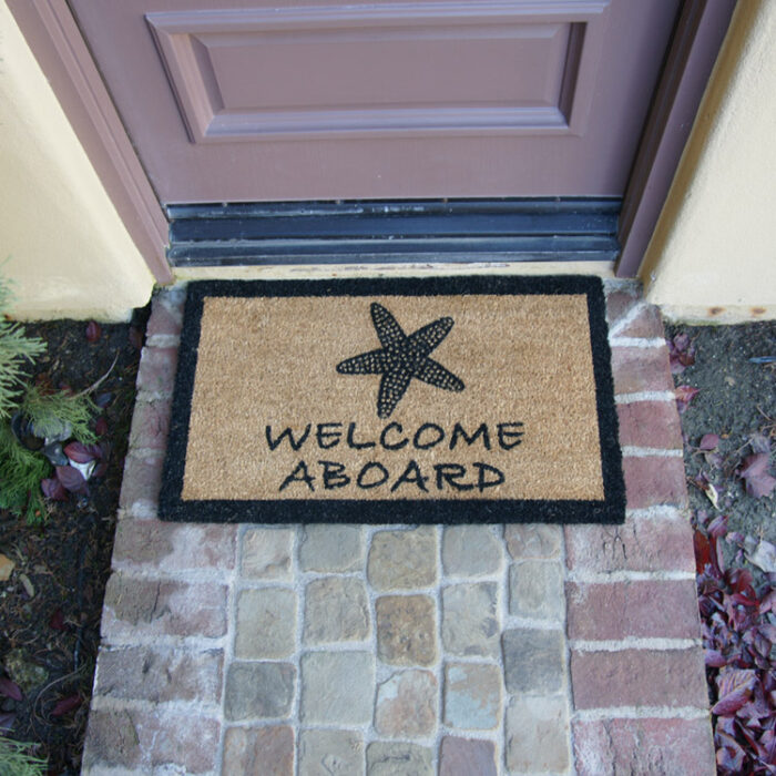 Welcome Aboard sign with sea side shell in front of brown door
