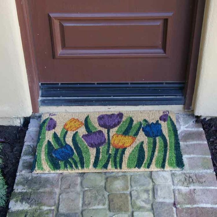 Handmade doormat with tulip garden design in front of dark brown door