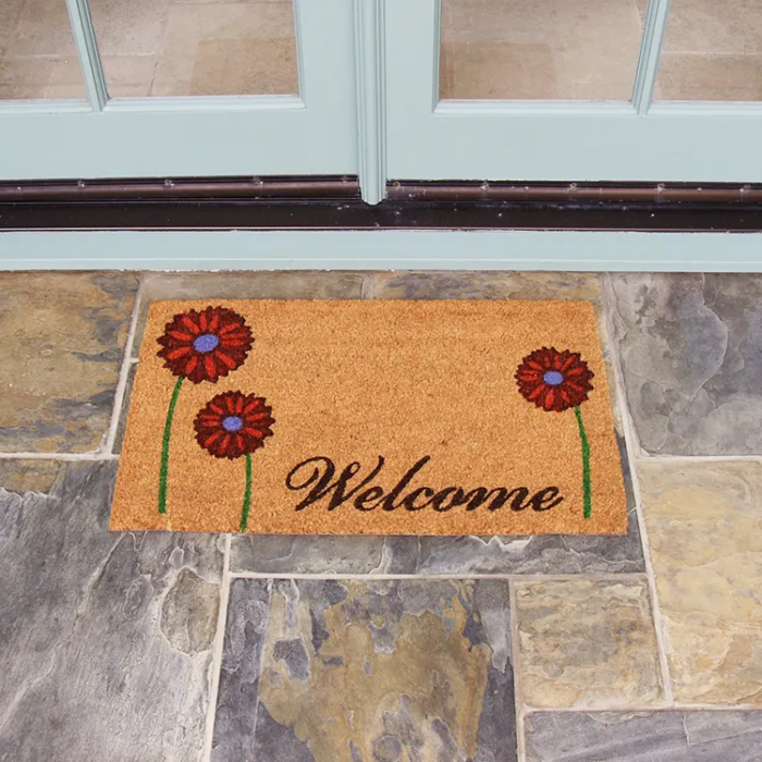 brown door mat with a red daisy design in front of white double doors