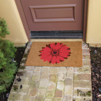 brown door mat with a red daisy design in front of brown door