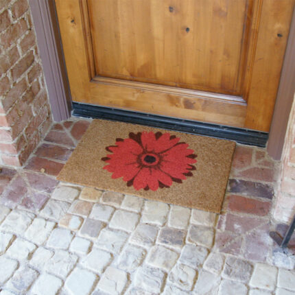 brown door mat with a red daisy design in front of brown light door