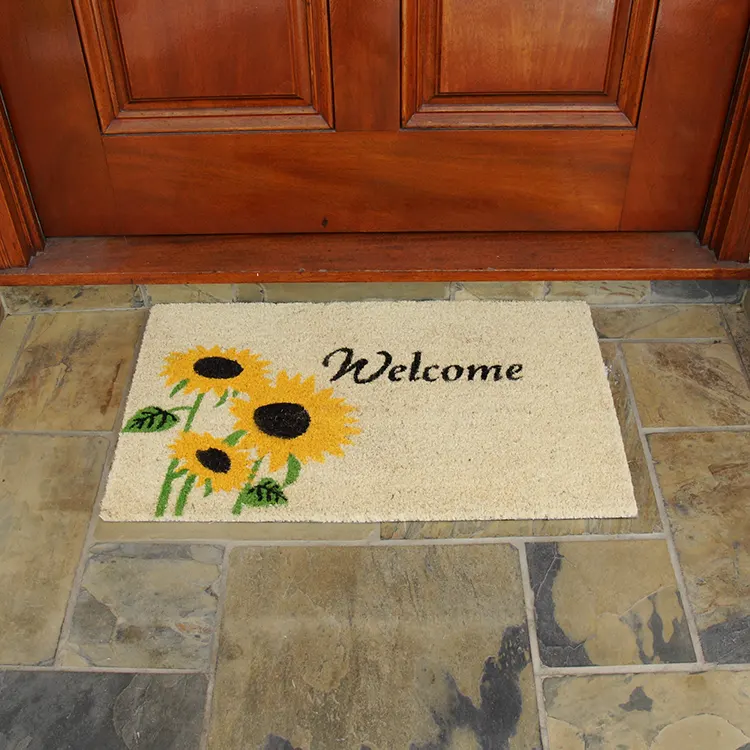 Welcome mat with sunflower design in front of red door