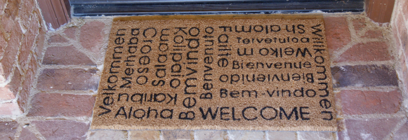 Welcome in many different languages splayed on a brown mat